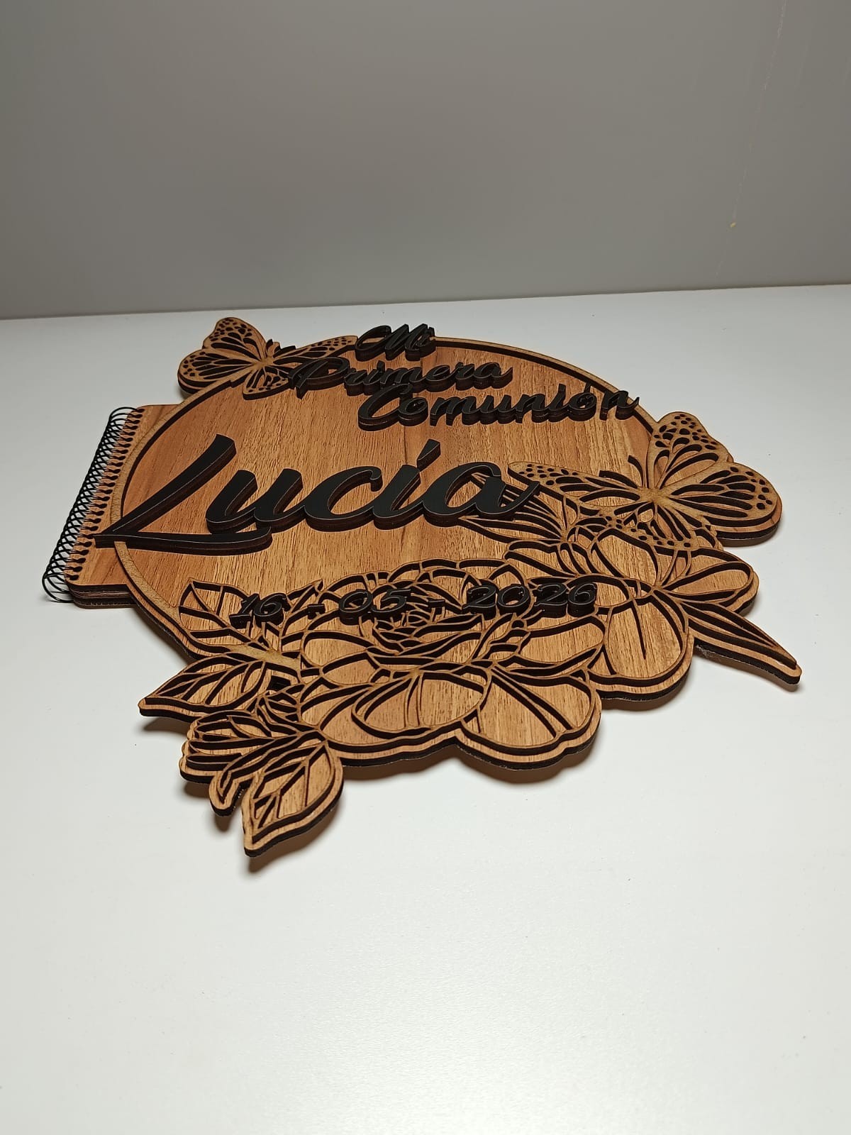 Álbum de comunión de madera con relieve 3D, flores, mariposas y nombre 'Lucía'. Izmi Láser Regalos Personalizados.