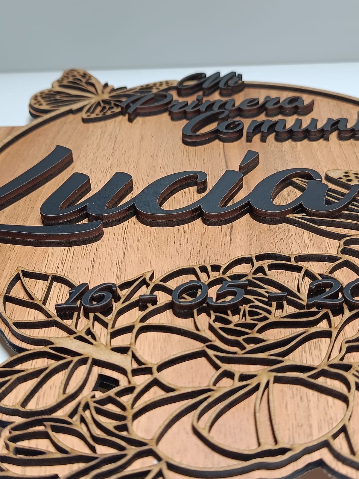 Izmi Láser Regalos Personalizados: Álbum de comunión en madera con nombre 'Lucía' y detalles 3D de mariposa y flores.